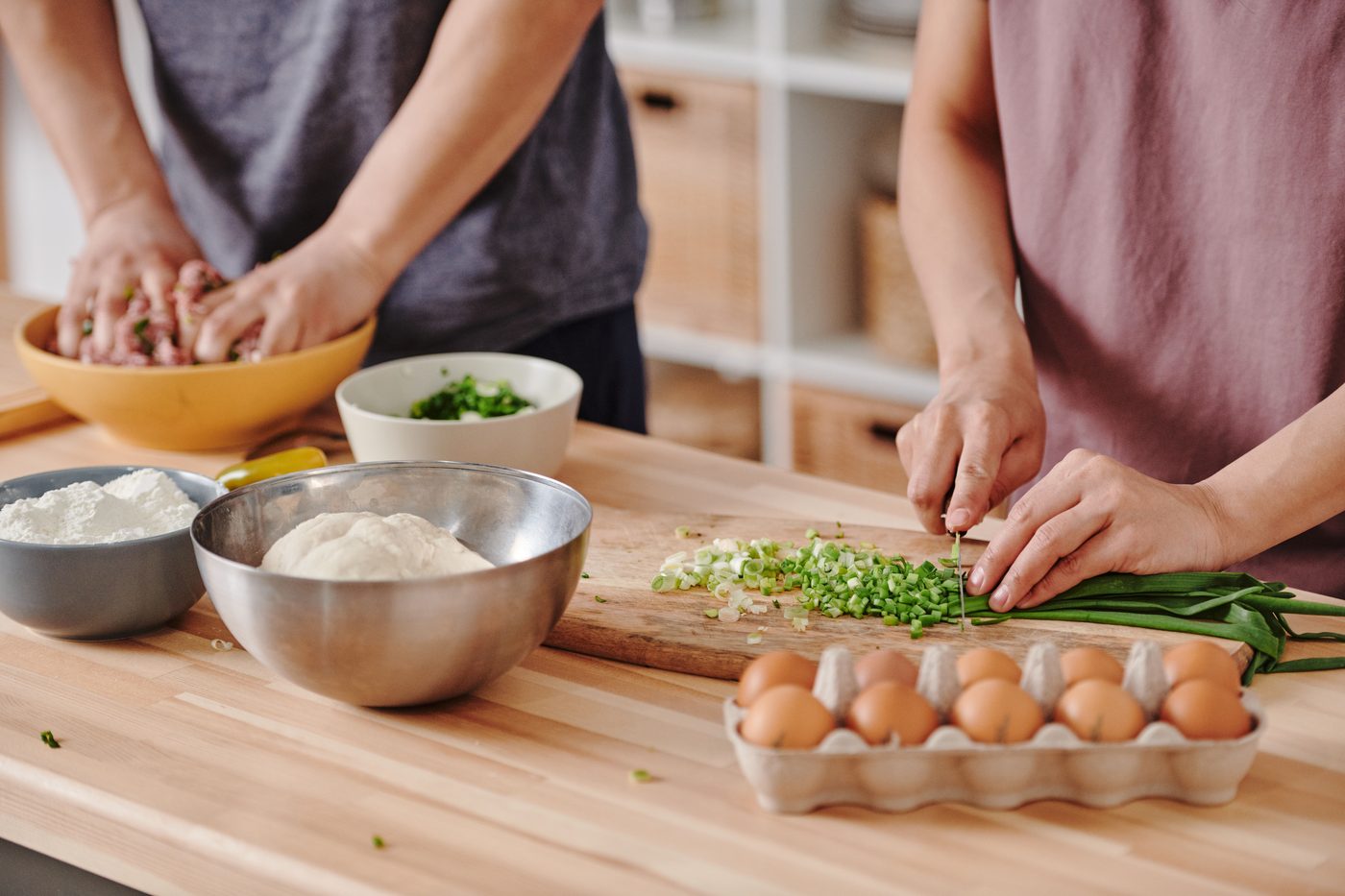 Two people cooking together at a kitchen counter, preparing fresh ingredients