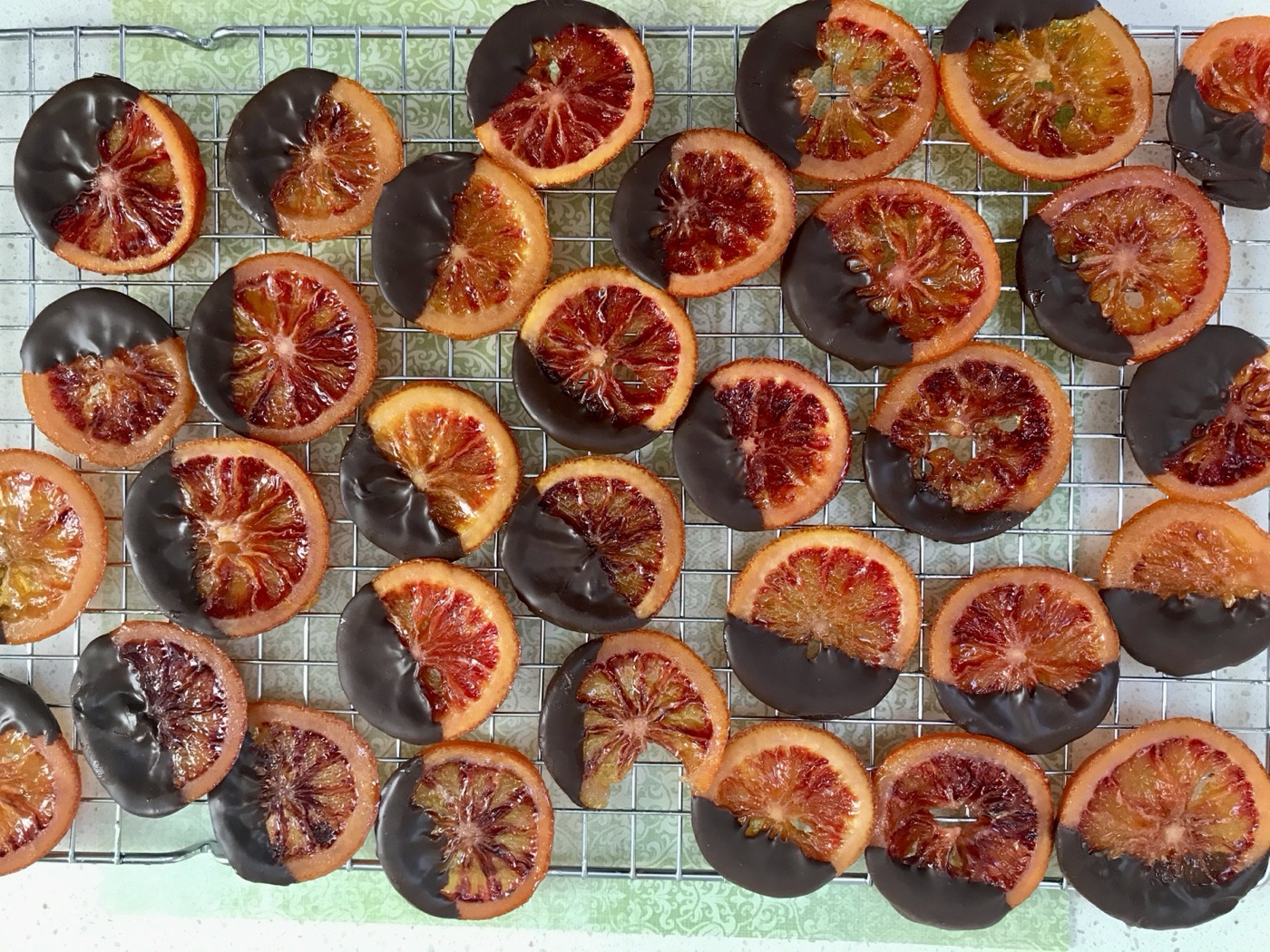Candied blood orange slices cooling on a wire rack