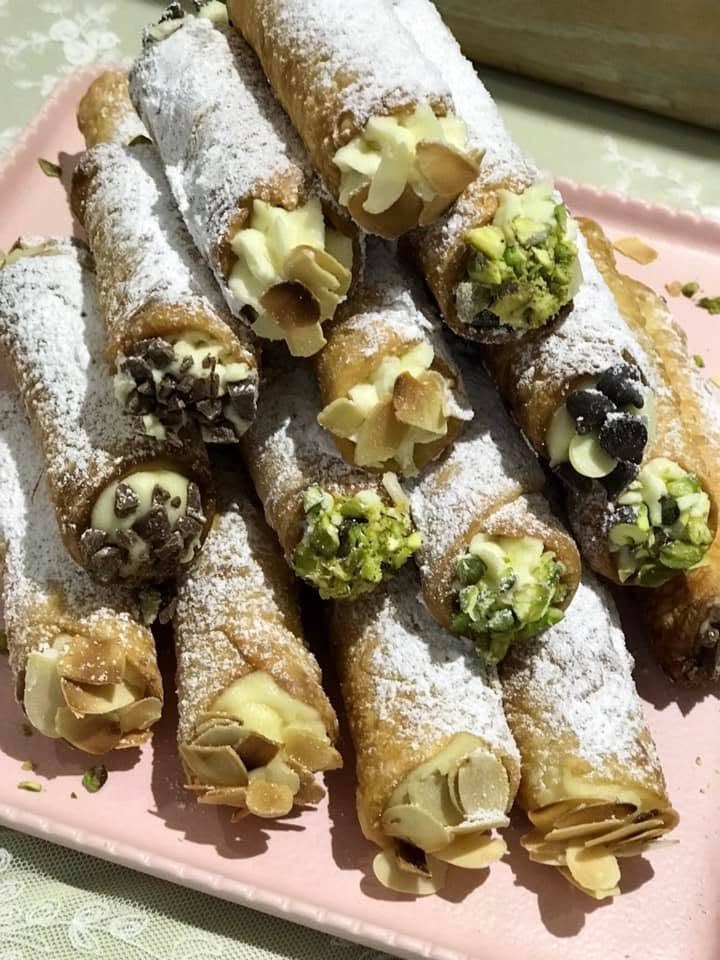 Cannoli dusted with icing sugar, ends dipped in pistachio and almond