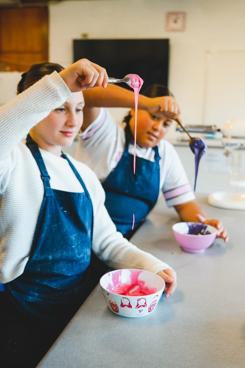 Sharing out bright pink icing between bowls at the decorating station