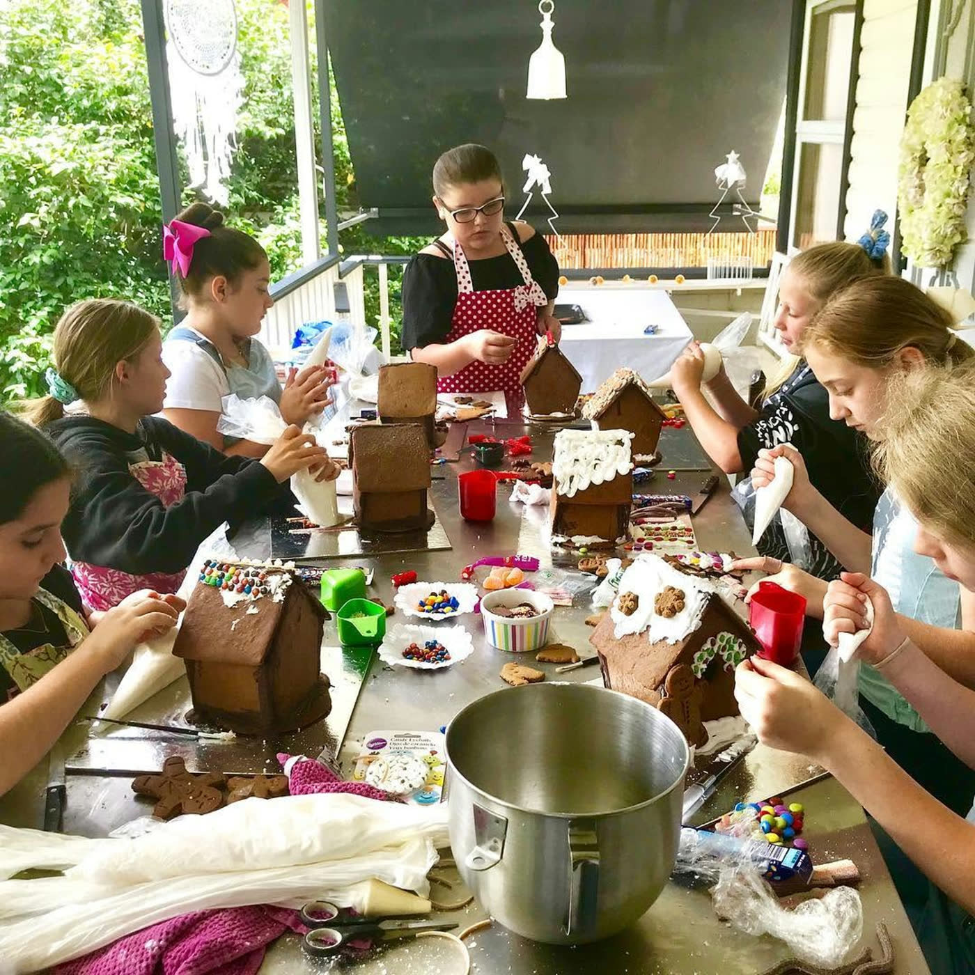 A table of gingerbread houses mid-decoration, lollies and icing everywhere