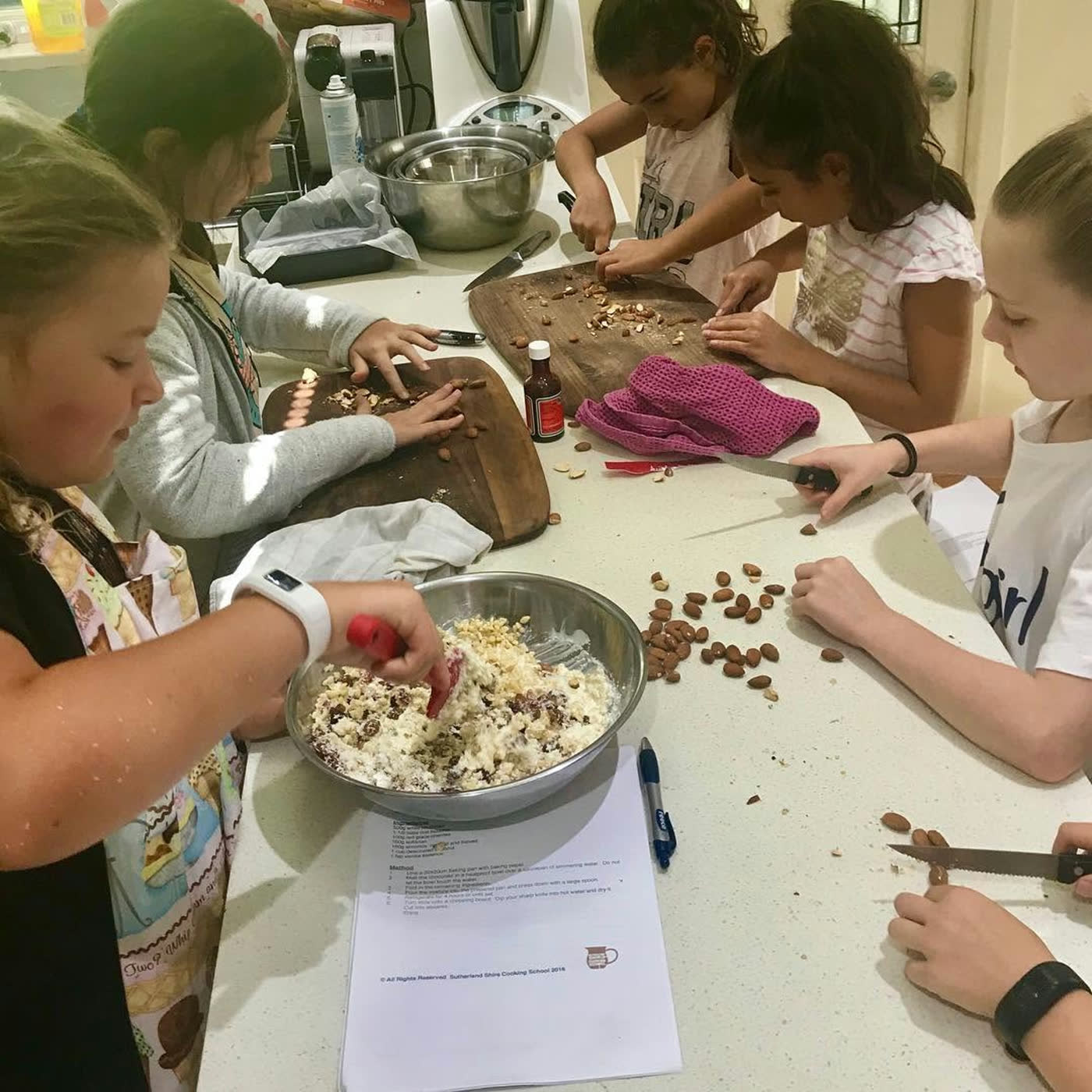 Two girls stirring a bowl of chocolate pieces together