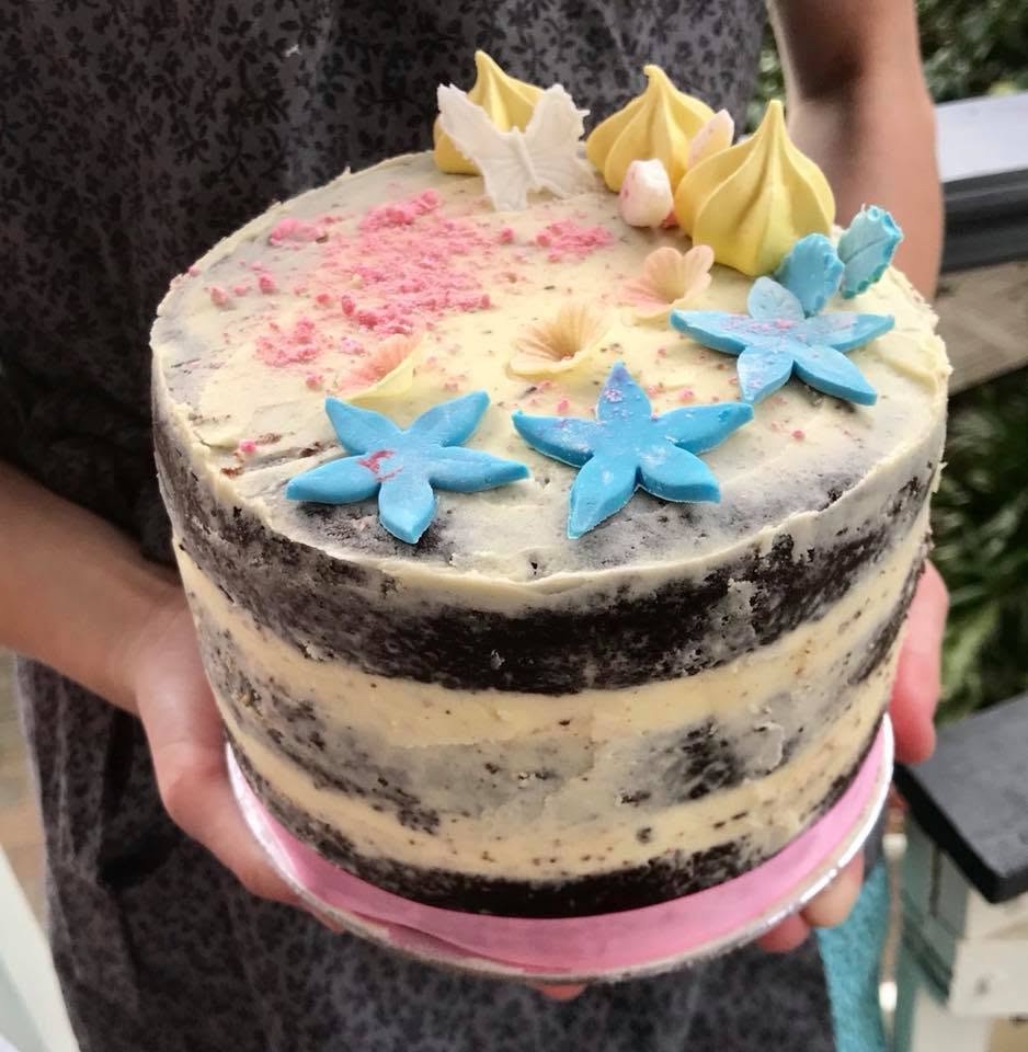 A semi-naked layer cake finished with blue sugar flowers