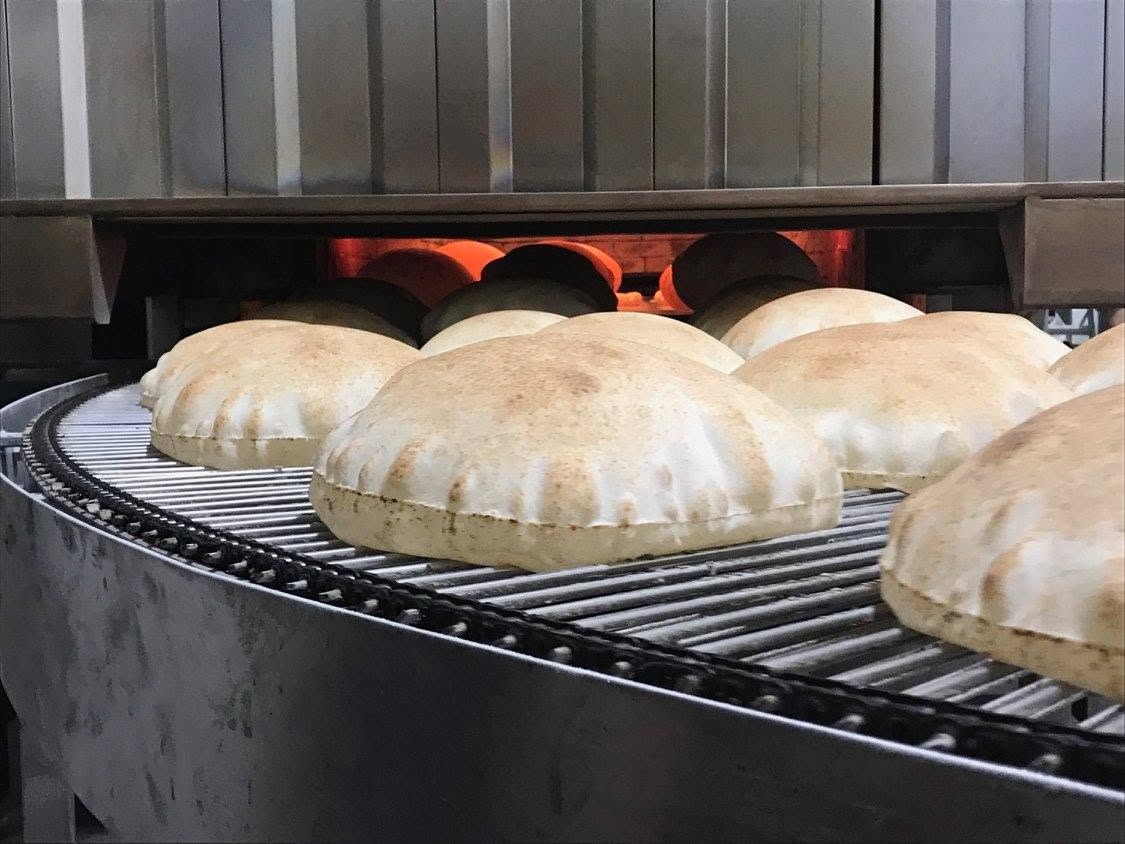 Puffed pita breads coming off the bakery conveyor