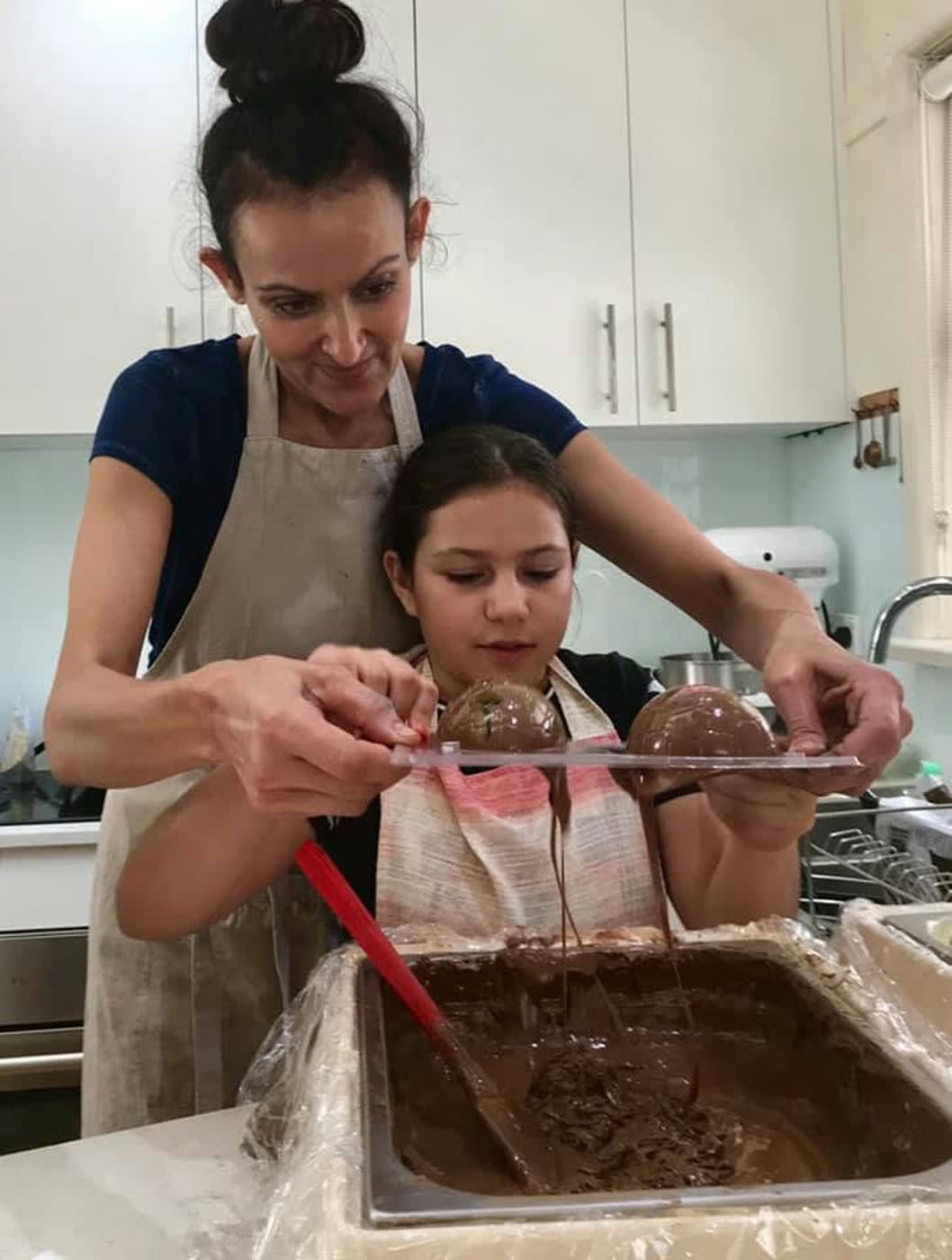 Melted chocolate being poured into a tray, a young helper holding it steady