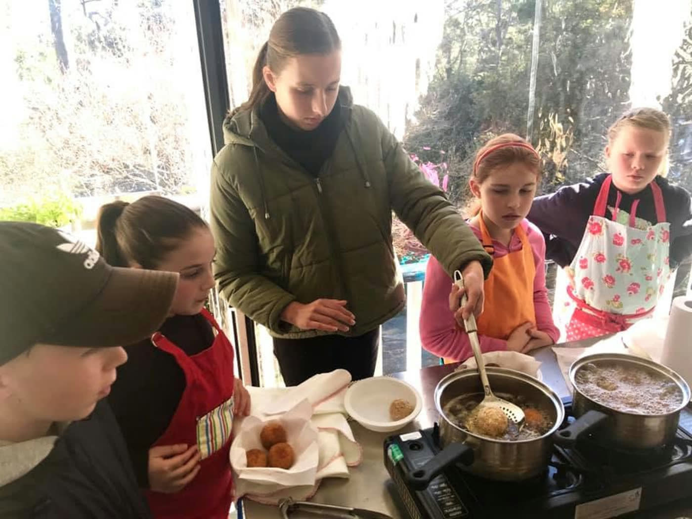 Cooking at the stove by the garden window, pots going and everyone watching